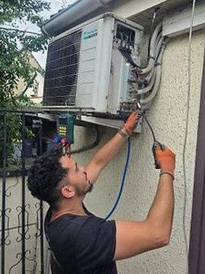 Technicien AK Solutions en cours de raccordement frigorifique sur une unité extérieure de climatisation